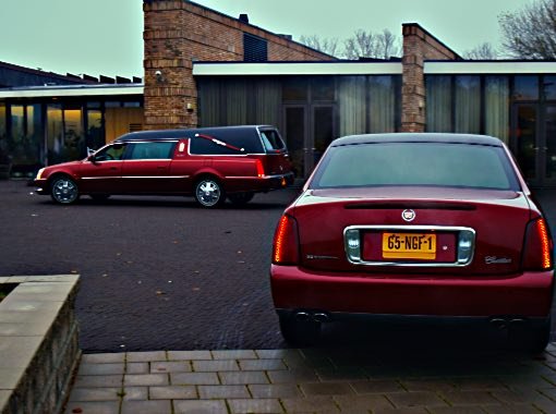 Vooraanzicht crematorium Zoetermeer met voorrijdend rode rouwauto Vooraanzicht crematorium Zoetermeer met voorrijdend rode rouwauto