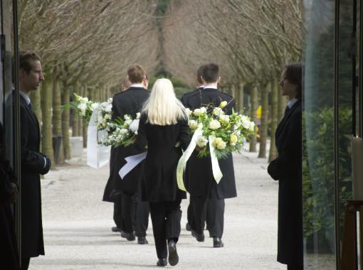 begrafenis met dragers en uitvaartleider met bloemen